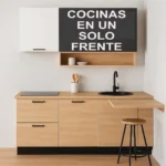 Cocina moderna de un solo frente con gabinetes en acabado madera clara, superiores en blanco y negro mate, placa de inducción, fregadero redondo negro y barra desayunador con taburete metálico, todo en un diseño compacto y minimalista.