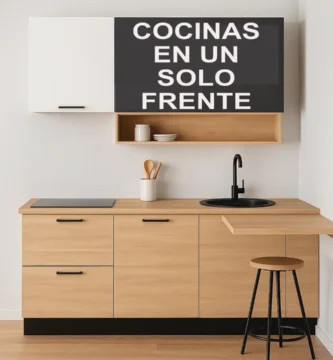 Cocina moderna de un solo frente con gabinetes en acabado madera clara, superiores en blanco y negro mate, placa de inducción, fregadero redondo negro y barra desayunador con taburete metálico, todo en un diseño compacto y minimalista.