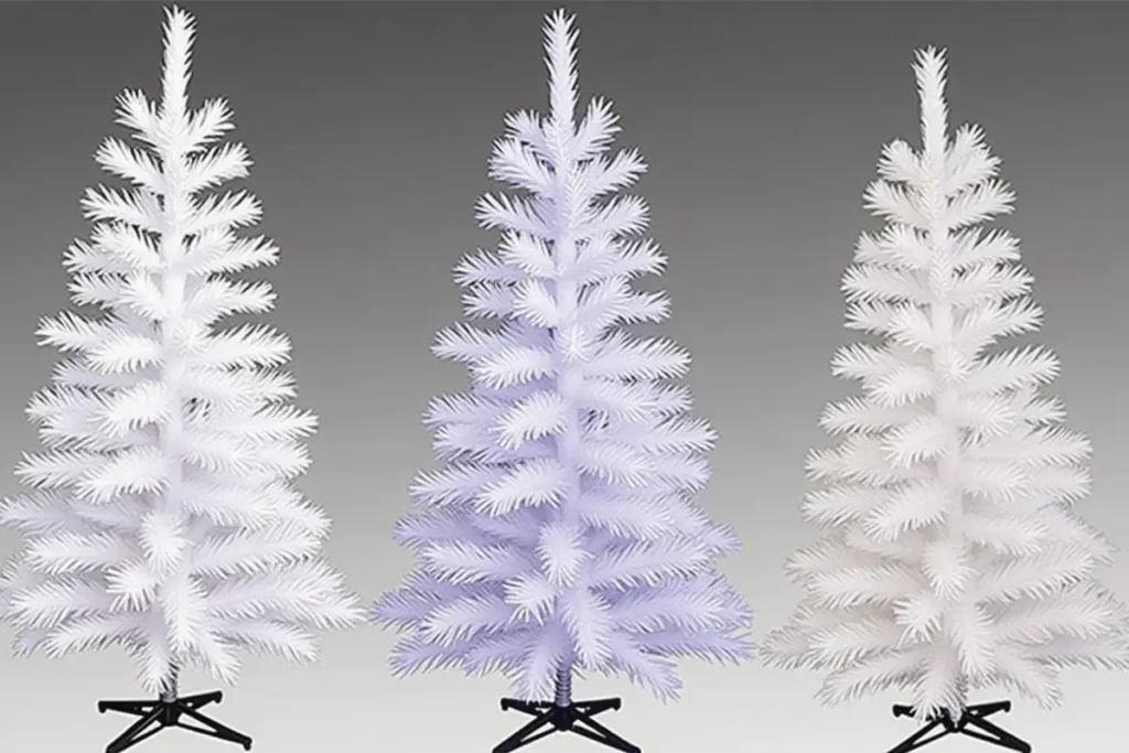 Árbol de Navidad nevado con adornos plateados en una sala moderna y luminosa, decoración elegante y tonos fríos.